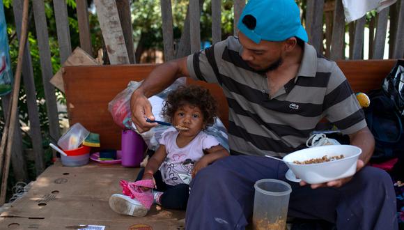 Un venezolano y su hija comen en el lado de una carretera en Boa Vista, estado de Roraima, Brasil.  (Foto: AFP)