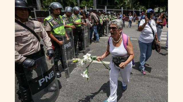 Una mujer de la oposición se enfrenta a la policía antidisturbios con unas flores, el 6 de mayo de 2017 en Caracas.(foto: Cristian Hernández).