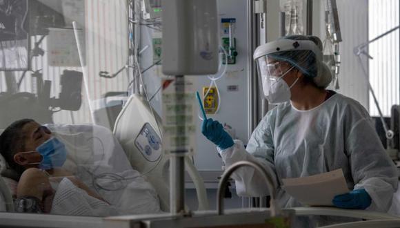 Un trabajador de salud realiza una videollamada con un familiar de un paciente infectado por COVID-19 de 21 años, quien permanece en una unidad de cuidados intensivos del Hospital Público El Tunal, en Bogotá, el 16 de junio de 2020. (AFP / Juan BARRETO).