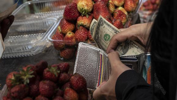 Una mujer guarda su cambio en billetes de un dólar después de comprar fruta en un puesto del mercado municipal Quinta Crespo en Caracas el 25 de agosto de 2022. (Foto de Yuri CORTEZ / AFP)