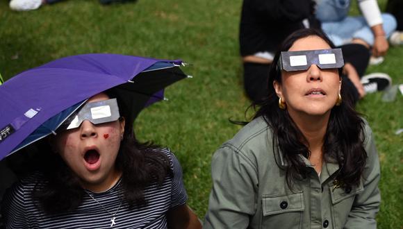 Unas mujeres viendo un eclipse solar con la protección requerida en la vista (Foto: AFP)
