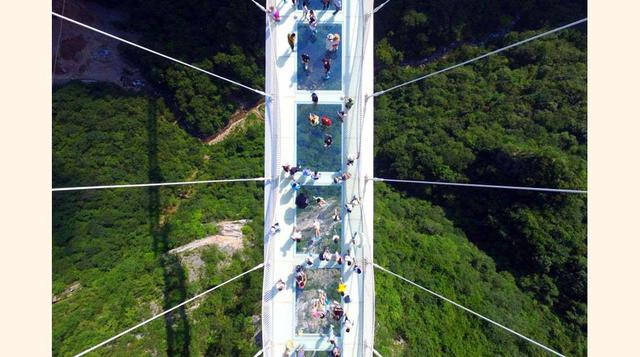 300 metros por encima del cañón, dompuesto por paneles de cristal de seis metros de ancho y tres capas de grosor (para mayor seguridad ante impactos inesperados sobre su transparente superficie), el puente de Zhangjiajie bate récords.(foto: ap).