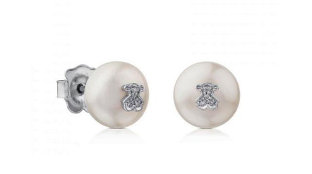 Aretes Puppies de Tous. Estos aretes de Tous retoman uno de los elementos preferidos para este tipo de mujer: las perlas. Los aretes son dos perlas de 9.5-10 milímetros, con la tradicional figura del osito Tous hecha de oro blanco engastado con diamantes 