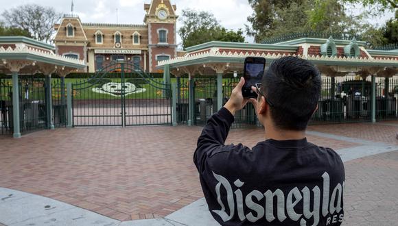 Un hombre toma una foto fuera de las puertas del parque Disneyland el primer día del cierre de los parques temáticos Disneyland y Disney California Adventure por el temor a la propagación del coronavirus. (Foto: AFP/David McNew)