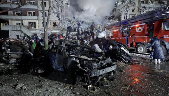 Esta fotografía tomada el 14 de enero de 2023 muestra un automóvil destruido y un edificio residencial que fueron destruidos por un ataque con misiles en Dnipro. (Foto de vitalii matokha / AFP)