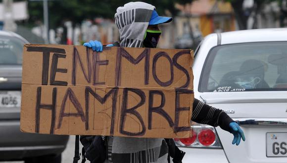 Un migrante venezolano sostiene un cartel que dice "Tenemos hambre" en las calles de Guayaquil, Ecuador, el 22 de abril de 2020, durante la pandemia del nuevo coronavirus, COVID-19. - Más de 180.000 personas en el mundo han muerto a causa del nuevo coronavirus desde que surgió en China en diciembre pasado, según un recuento de la AFP basado en fuentes oficiales. (Foto de José SÁNCHEZ / AFP)