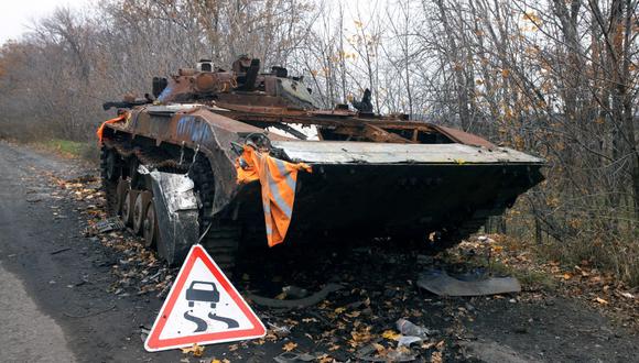 Una fotografía muestra una señal de tráfico junto a un vehículo blindado de transporte de personal ruso dañado en una carretera cerca de Vovchans'k, región de Kharkiv, el 1 de noviembre de 2022, en medio de la invasión rusa de Ucrania. (Foto de Yevhen TITOV / AFP)