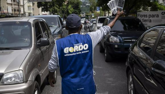 Un vendedor ofrece boletos de lotería a los conductores que pasan por una de las avenidas del barrio de Altamira en Caracas. (Foto: AFP)