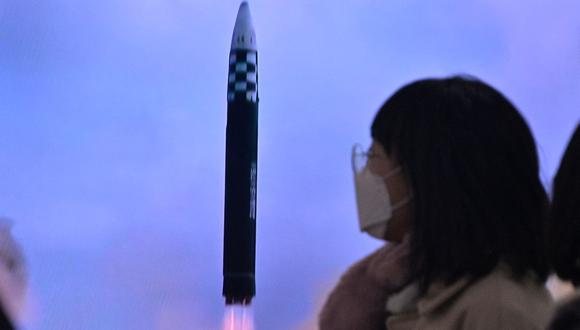 Una mujer pasa frente a un televisor que muestra un noticiero con imágenes de archivo de una prueba de misiles de Corea del Norte, en una estación de tren en Seúl el 18 de febrero de 2023. (Foto de Anthony WALLACE / AFP)