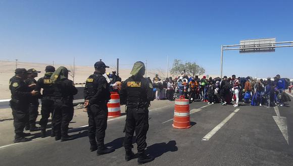 A group of migrants of various nationalities is stopped at the border by Peruvian police in Tacna, Peru, on April 13, 2023. - Dozens of Venezuelans, Haitians and Ecuadorians, among other nationalities, were stopped by Peruvian police officers at the border with Chile, after the migrants, with no documents, left that country. "In Chile they no longer want us," says Marina Arellano, a Venezuelan migrant who decided to go back to her country. (Photo by Javier Rumiche / AFP)