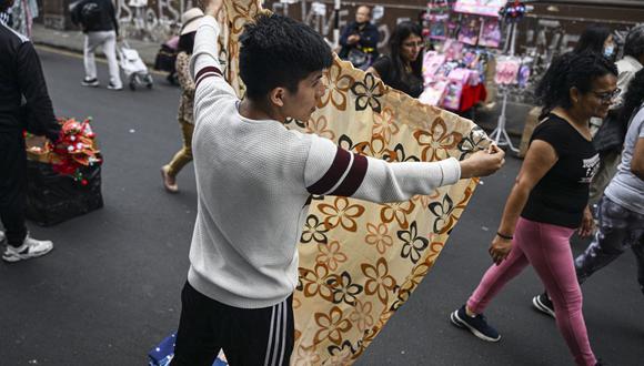 Un hombre vende cortinas de baño en el centro de Lima el 23 de diciembre de 2022. (Foto de Ernesto Benavides / AFP)