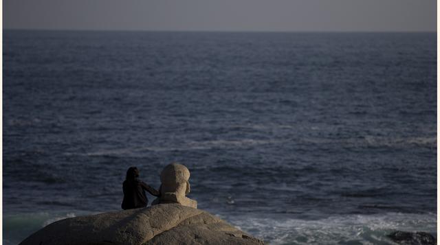 Una persona se sienta junto a un busto del poeta ganador del Premio Nobel Pablo Neruda levantado de cara al mar, frente a la casa-museo del poeta en Isla Negra (Chile). Neruda amaba el mar y pidió ser enterrado en la casa situada en un promontorio rocoso 