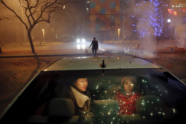 Una madre y su hija se sientan dentro del coche mientras observan los fuegos artificiales y los petardos durante la celebración del Año Nuevo Chino. (Foto Reuters)