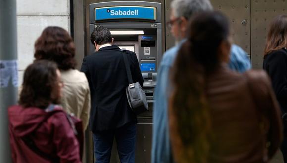 Un cliente saca dinero de un cajero automático del Banco Sabadell en Barcelona. (Foto: AFP)