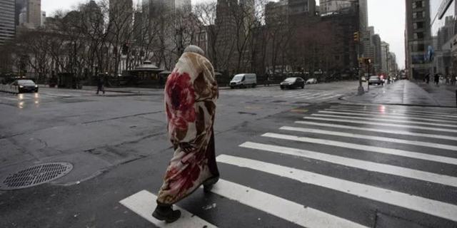 FOTO 1 | Un hombre envuelto en una manta cruza la calle 42 en la Sexta Avenida, que suele ser una intersección peatonal muy concurrida en una mañana. (Foto: AP)