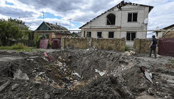 Esta fotografía tomada el 7 de septiembre de 2022 muestra un cráter frente a una casa dañada en Siversk, región de Donetsk, en medio de la invasión rusa de Ucrania. (Foto por Juan BARRETO / AFP)