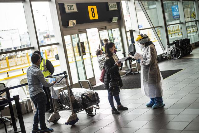 Los pasajeros están siendo revisados ​​por un trabajador de salud en el aeropuerto internacional Jorge Chávez en Lima. Imagen del 17 de julio de 2020. (ERNESTO BENAVIDES / AFP).