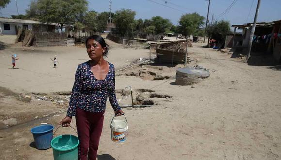 Una mujer carga baldes con agua de los bidones instalados por Acción contra el Hambre, el 6 de septiembre de 2023 en el asentamiento humano de Mocará, departamento de Piura (Perú). Foto: EFE
