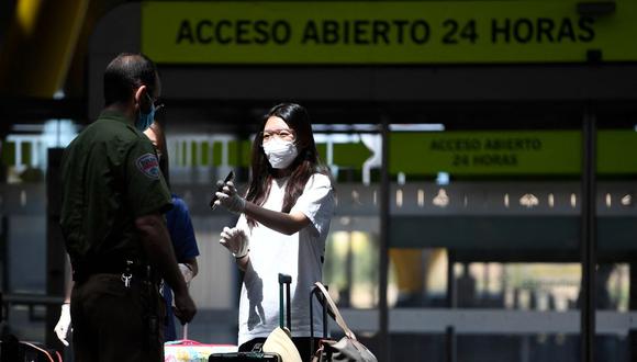 Una pasajera con una máscara facial muestra sus documentos en su teléfono a un oficial de seguridad en el aeropuerto de Barajas en Madrid, España, el 20 de junio de 2020. (Foto: PIERRE-PHILIPPE MARCOU / AFP).