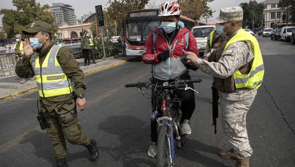 Soldados y policías detienen a ciclista en un puesto de control en Santiago (Chile), el 25 de marzo de 2021, en medio de la pandemia COVID-19. (Martin BERNETTI / AFP).