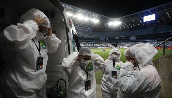 El personal de ambulancia con trajes protectores en medio de la pandemia del nuevo coronavirus COVID-19 espera en el estadio vacío Arena do Gremio en Porto Alegre, Brasil. (Foto de DIEGO VARA / AFP)