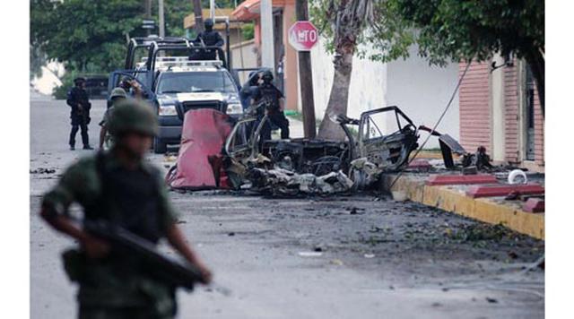 Victoria, México. Homicidios: 117. Población: 345.080. Tasa de homicidios: 33.91. En la imagen: Policías mexicanos y un soldado hacen guardia junto a los restos de un auto estacionado afuera de la emisora Televisa en Ciudad Victoria, en el estado de Tamau