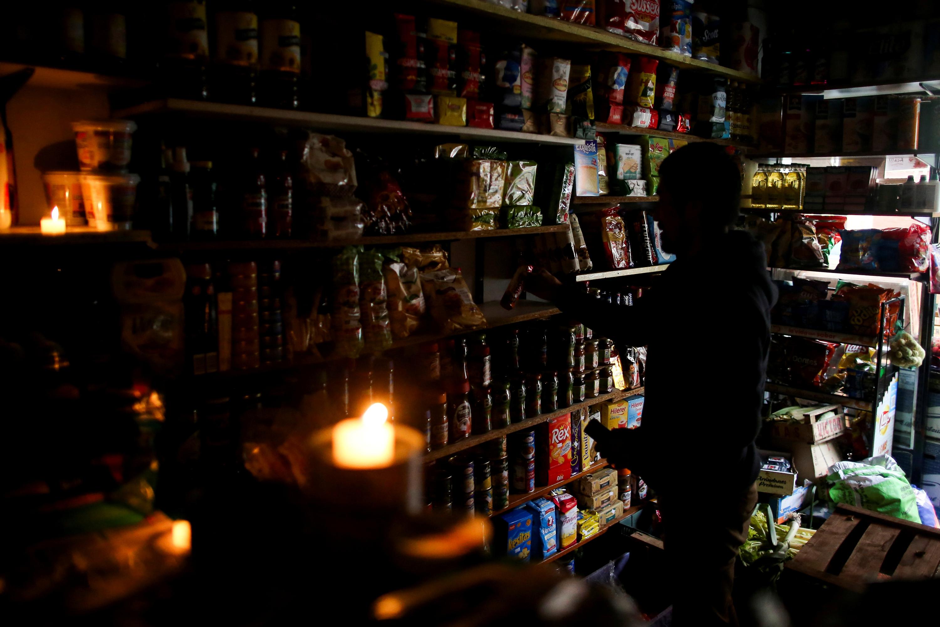Las tiendas atienden con velas ante la falta de luz. (Foto: Reuters)