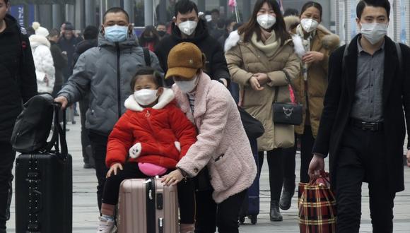 Travelers wear face masks as they walk outside a train station in Yichang in southern China's Hubei province, Tuesday, Jan. 21, 2020. Face masks sold out and temperature checks at airports and train stations became the new norm as China strove Tuesday to control the outbreak of a new virus that has reached four other countries and territories and threatens to spread further during the Lunar New Year travel rush. (Chinatopix via AP)