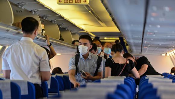 Los pasajeros, que usan mascarillas como medida preventiva contra el coronavirus, abordan un vuelo a la ciudad china central de Wuhan, en el Aeropuerto Internacional de Pudong en Shanghái. Imagen del 14 de julio de 2020. (AFP / Hector RETAMAL)