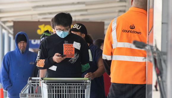 Un hombre (centro) con una mascarilla espera entrar a un supermercado para comprar suministros en Wellington, Nueva Zelanda, el 24 de marzo de 2020. (Marty MELVILLE / AFP / Referencial).