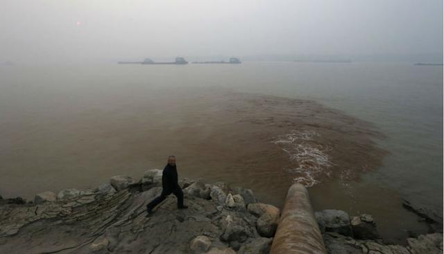 Un hombre camina junto a tuberías que vierten deshechos al río Yangtze. Para ‘El País’ de España, 20 millones de chinos consumen agua con arsénico. (Foto: William Hong)