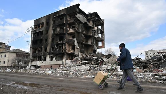 (ARCHIVOS) En esta foto de archivo tomada el 4 de abril de 2022, un hombre empuja un carro frente a edificios destruidos en la ciudad de Borodianka, al noroeste de Kyiv, en medio de la invasión rusa de Ucrania. - AFP presenta un paquete de 60 fotografías de archivo que muestran la vida cotidiana de los ucranianos durante los seis meses de la invasión rusa. (Foto de Sergei SUPINSKY / AFP)