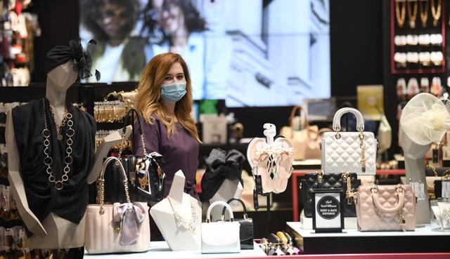 Un vendedor, que usa una máscara para protegerse contra el coronavirus, se encuentra junto a los bolsos de mujer que se muestran a la venta en una tienda del Dubai Mall. (AFP / Karim SAHIB).