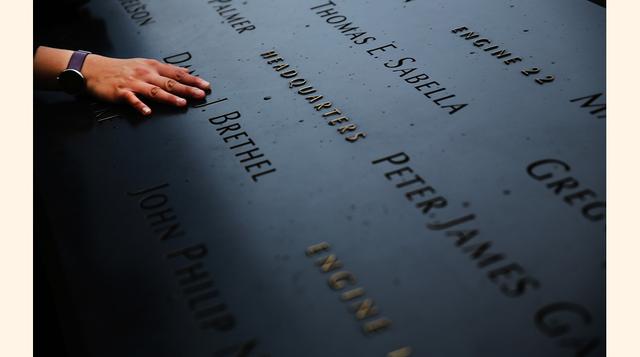 Una mujer pone su mano sobre los nombres de las víctimas grabados en el monumento de la Zona Cero en Nueva York.