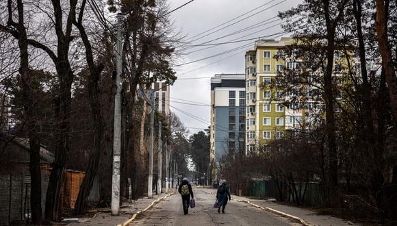 Una pareja camina por una calle mientras huyen de la ciudad de Irpin, al noroeste de Kiev, el 13 de marzo de 2022. (Foto: Dimitar DILKOFF / AFP)