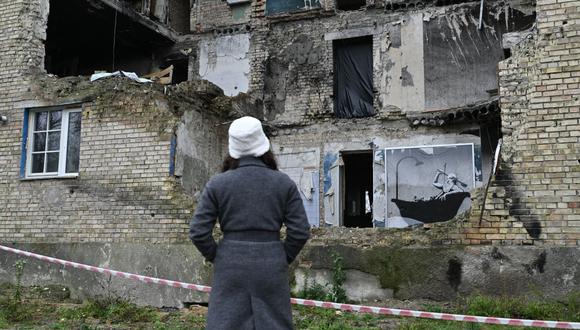 Una mujer mira un grafiti realizado por Banksy en la pared de un edificio muy dañado en el pueblo de Gorenka, cerca de Kyiv, en medio de la invasión rusa de Ucrania. (Foto de Genya SAVILOV / AFP)
