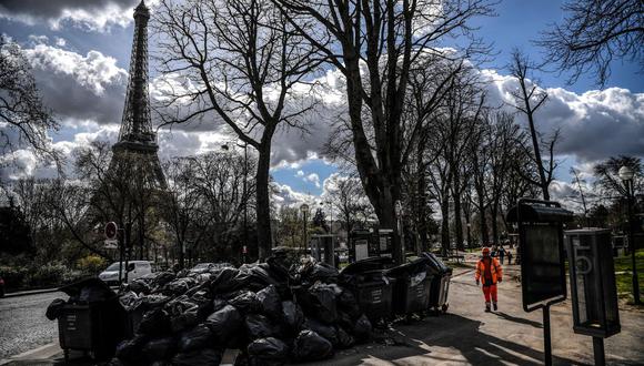 Un trabajador pasa frente a la torre Eiffel en París el 15 de marzo de 2023. (Foto de Christophe ARCHAMBAULT / AFP)