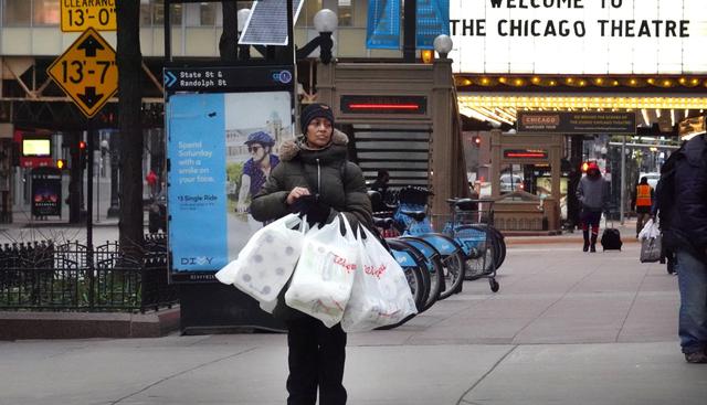Una mujer es vista el 20 de marzo de 2020 en el distrito comercial de Loop, Chicago con bolsas de papel higiénico. (AFP).