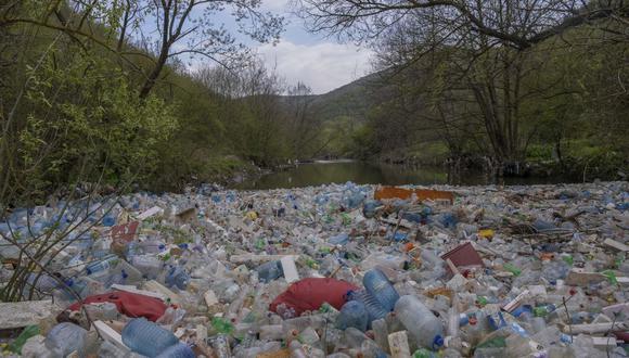 Botellas de plástico tiradas y otra basura flotan a lo largo del río Morava en el pueblo de Pogragje cerca de la ciudad de Gjilan, el 22 de abril de 2023. (Foto de Armend NIMANI / AFP)