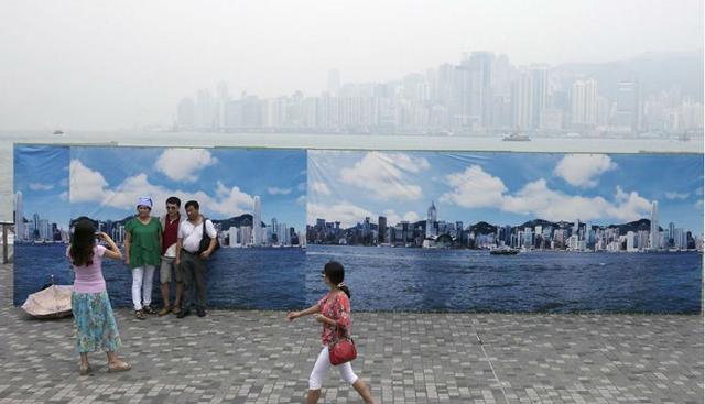 Un grupo de turistas posa junto a un falso panel del paisaje de Hong Kong, debido a que la polución no les permite tomar buenas fotografías. (Foto: Molly Smith)