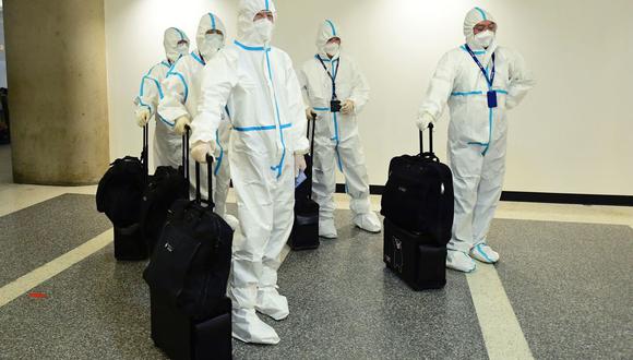 La tripulación de vuelo de Air China llega con trajes para materiales peligrosos a la terminal internacional del Aeropuerto Internacional de Los Ángeles. (Foto de Frederic J. BROWN / AFP)