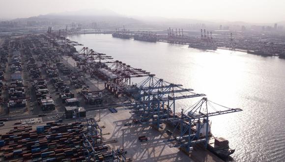 Buques de carga debajo de grúas en el terminal de contenedores de Qingdao, Qianwan, en esta fotografía aérea tomada en Qingdao, China, el lunes 7 de mayo de 2018.