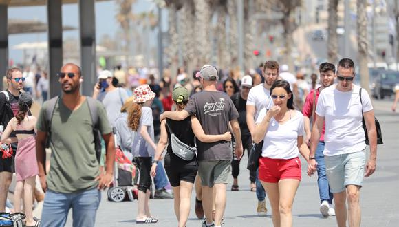 Las personas caminan sin mascarillas cerca de la playa en Tel Aviv. Israel puso fin al uso obligatorio de mascarillas al aire libre tras una exitosa campaña de vacunación contra el coronavirus. (Foto: EFE / EPA / ABIR SULTAN),