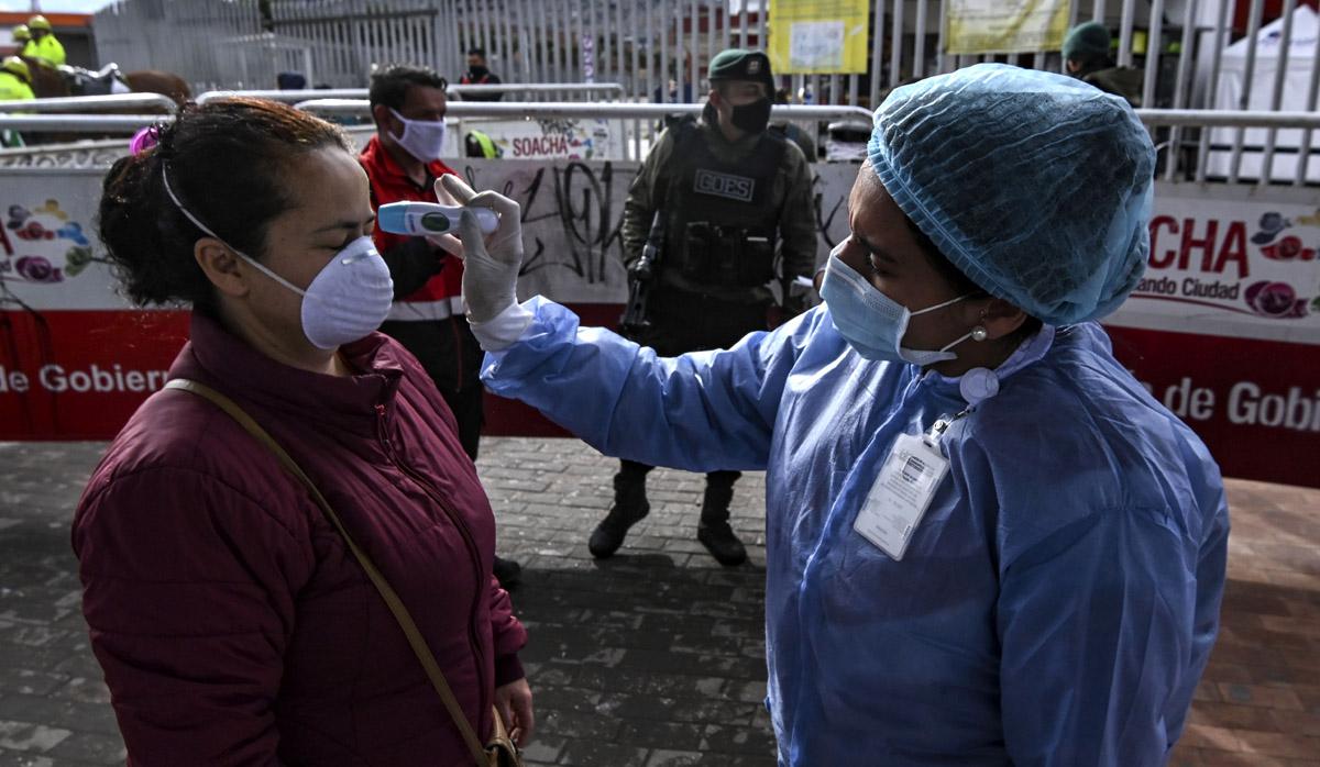 Una mujer usa una máscara facial mientras se controla su temperatura como medida preventiva contra la propagación del nuevo coronavirus en Bogotá. (AFP/Juan Barreto)