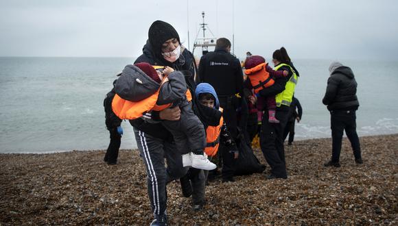 Una migrante carga a sus hijos después de ser ayudada a desembarcar desde un bote salvavidas de la RNLI (Royal National Lifeboat Institution) en una playa de Dungeness, en la costa sureste de Inglaterra, después de ser rescatado mientras cruzaba el Canal de la Mancha. (Foto de Ben STANSALL / AFP)