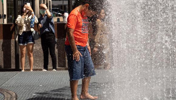 La gente juega en la escultura a base de agua del artista Jeppe Hein titulada "Changing Spaces" en el Rockefeller Center Plaza en la ciudad de Nueva York el 19 de julio de 2022, mientras la ola de calor continúa en Europa y América del Norte. (Foto de Yuki IWAMURA / AFP)