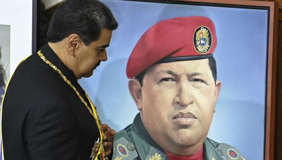 El presidente de Venezuela, Nicolás Maduro, pasa junto a un retrato del difunto presidente Hugo Chávez mientras presenta su informe anual a la Asamblea Nacional en Caracas. (Foto por YURI CORTEZ / AFP)