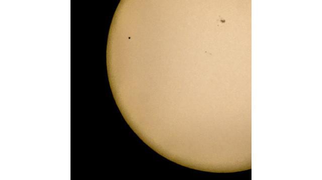 El planeta Mercurio, que en la foto se observa arriba a la izquierda como un pequeño punto negro pasando adelante del Sol, es visto con ayuda de un telescopio instalado en Estocolmo, Suecia. Por primera vez en 10 años, Mercurio pasó el lunes directamente 