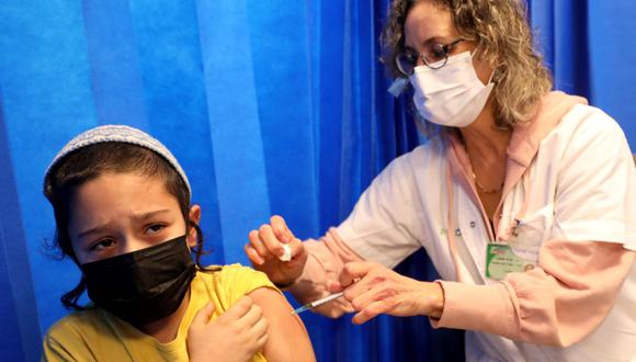 Una trabajadora de la salud israelí administra una dosis de la vacuna Pfizer-BioNTech contra el coronavirus a un niño en la ciudad de Modiin, en el centro de Israel, el 2 de enero de 2022. (GIL COHEN-MAGEN / AFP).
