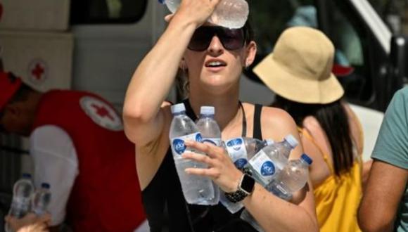 Las personas se refrescan con botellas de agua fría distribuidas por la Cruz Roja en Atenas. Foto: Swissinfo